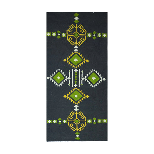 A dark gray rug with a repeating pattern of green and gold geometric shapes. The pattern is symmetrical and features stylized floral and diamond motifs.
