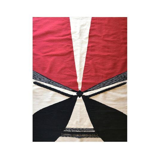 A textile featuring a geometric design with bold colors, primarily red, white, and black. The pattern includes triangular shapes converging towards the center, creating a dynamic and striking visual effect. The texture appears woven, adding depth to the overall composition.