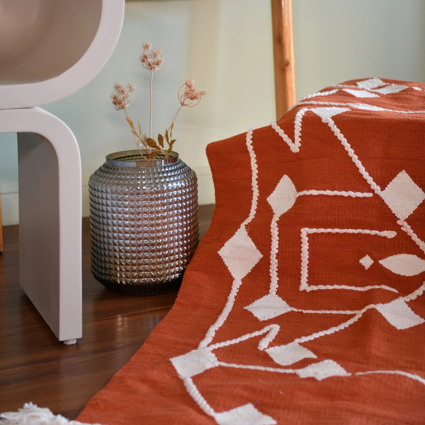 This 1 x 1.5 meter rug features a bold, Coral background and a striking white geometric pattern that consists of interconnected diamond shapes, creating a visually engaging composition. The edges are adorned with fringed tassels made of the same material, contributing to the traditional and artisanal aesthetic.