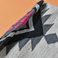 "Close-up of a woven tote bag with a geometric pattern in black, white, and gray, with a pink detail."