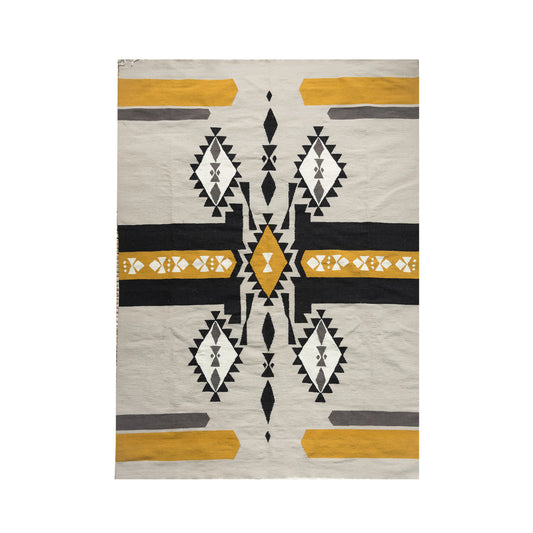 A rectangular area rug with an intricate geometric pattern in earthy tones. The design features bold black, white, and yellow shapes, including diamonds and zigzags, arranged symmetrically across the surface. The rug adds a striking visual element, perfect for enhancing a contemporary or rustic decor style.