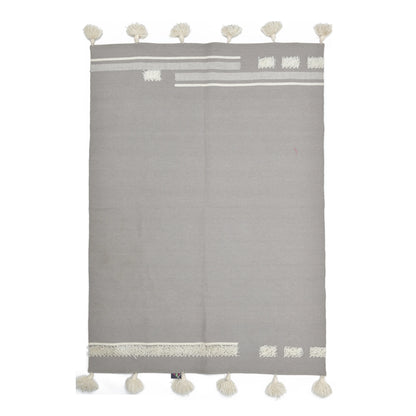 A rectangular gray rug with decorative white tassels along the bottom edge and various textured patterns in white at the top and sides. The design features stripes and geometric shapes, creating a modern and minimalist aesthetic.